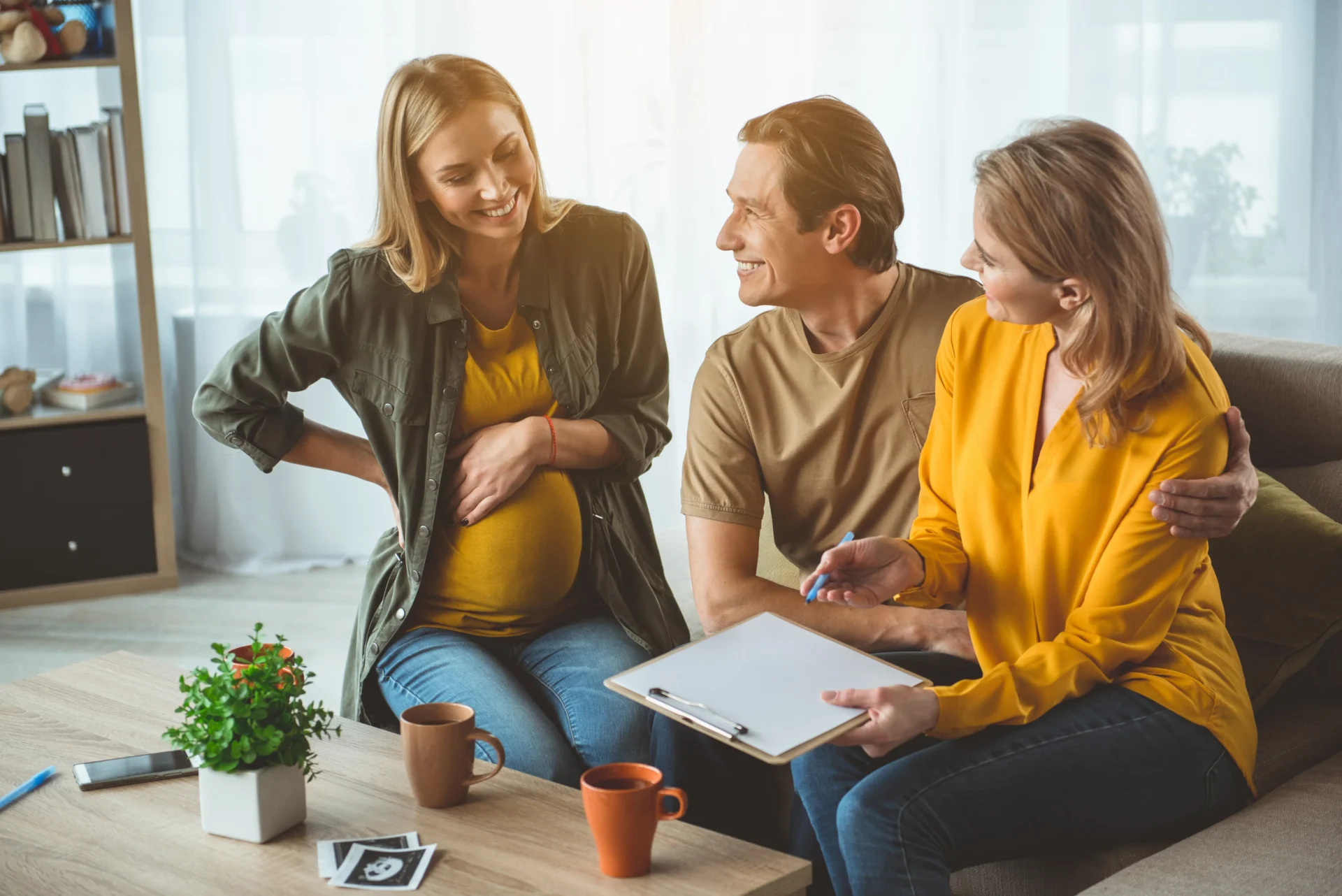 A couple sit on a sofa with their surrogate.
