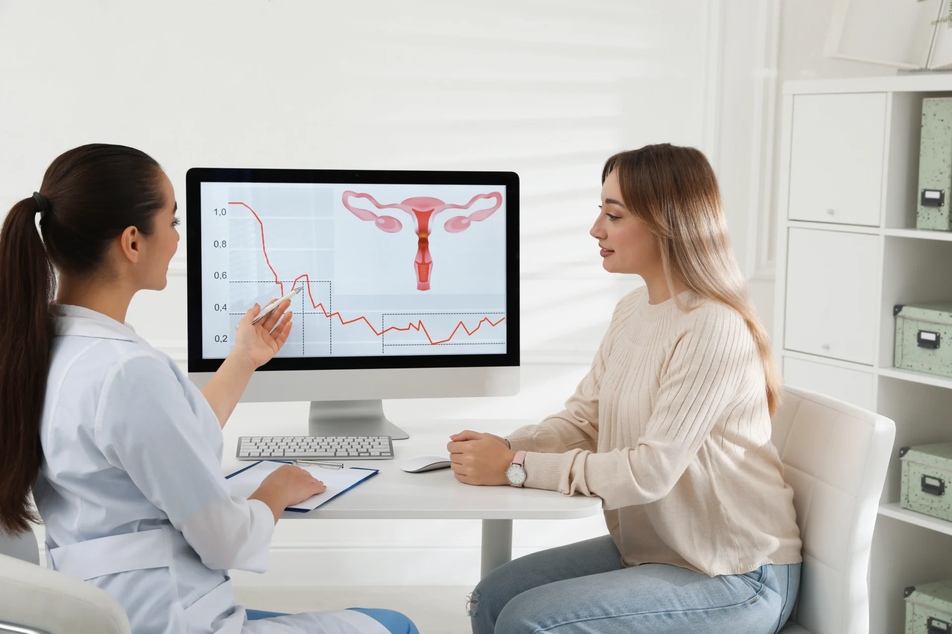 A fertility specialists shows a female patient a computer screen with a diagram of ovaries.