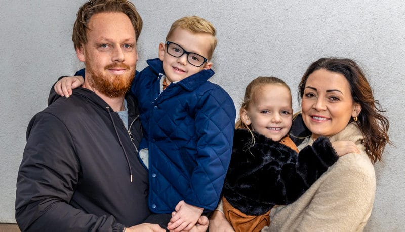 A mother and father holder their two young children, a girl and a boy.