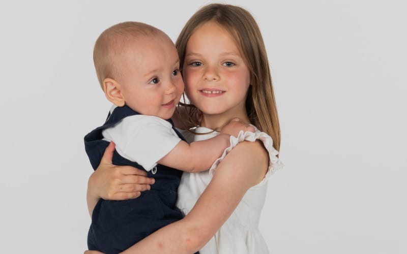 Young girl holds baby.