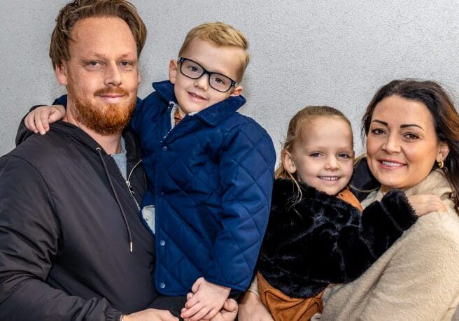 A mother and father holder their two young children, a girl and a boy.